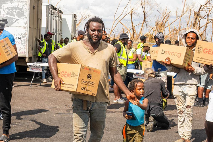 Community members in Jamaica carry boxes of donated goods distributed by Good360 and GEM after Hurricane Melissa, demonstrating the impact of disaster recovery donations.