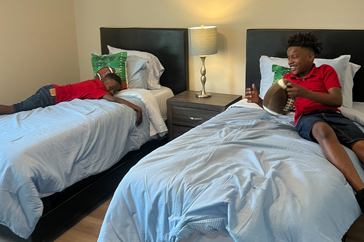 Children enjoy newly donated beds from High Socks for Hope and Good360, demonstrating how home essentials donations support families rebuilding stability.