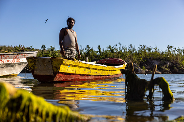 A fisherman stands in a damaged boat as coastal communities in Jamaica work to restore livelihoods after Hurricane Melissa.