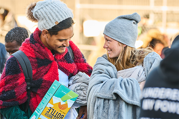 Two individuals share a moment while receiving clothing and essential items during a Las Vegas outreach event supporting people experiencing homelessness.