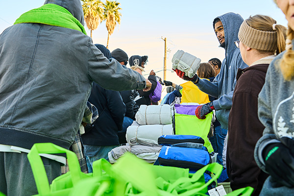 Volunteer distributes blankets and essential supplies to individuals at a Las Vegas community relief event supported by Good360 and nonprofit partners.
