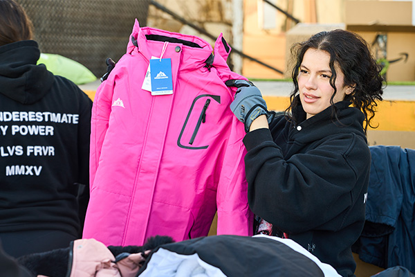 Volunteer holds a new winter jacket available for individuals to select during a Las Vegas clothing distribution event.