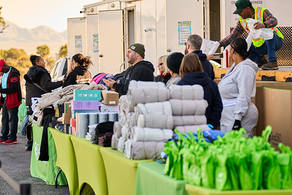 Good360 volunteer organizes clothing and blankets during a Las Vegas community relief event supporting individuals experiencing homelessness.