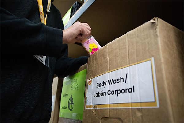 A WellPower staff member places a tropical-scented body wash into a labeled donation box at WellPower's Shopette in Denver, Colorado.