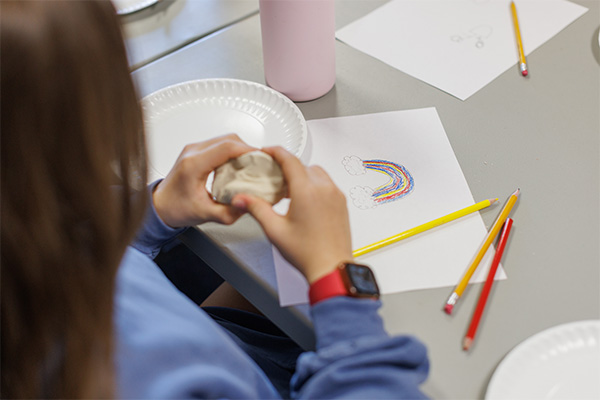 A child squeezes a stress ball next to a hand-drawn rainbow during a Project:Camp art activity in London, Kentucky
